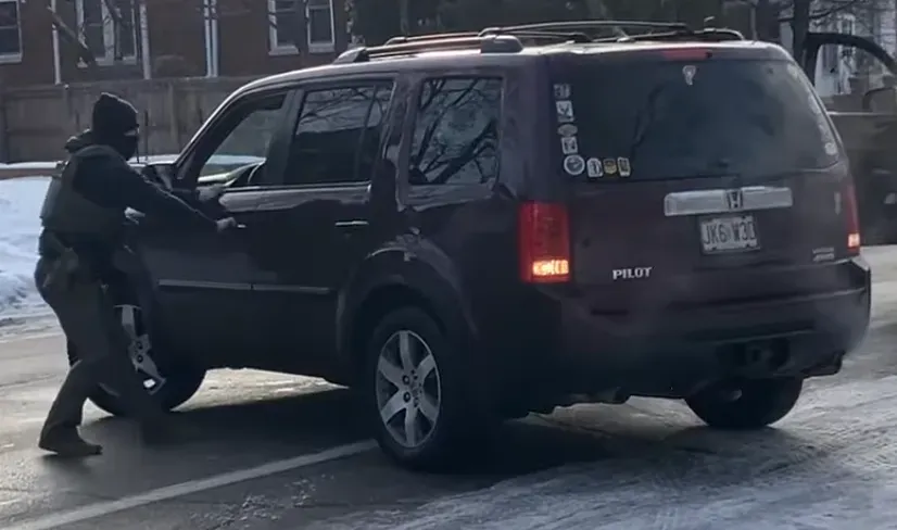 A masked ICE agent attempts to open the driver-side door of Renée Good's unmoving vehicle