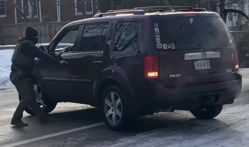 A masked ICE agent attempts to open the driver-side door of Renée Good's unmoving vehicle