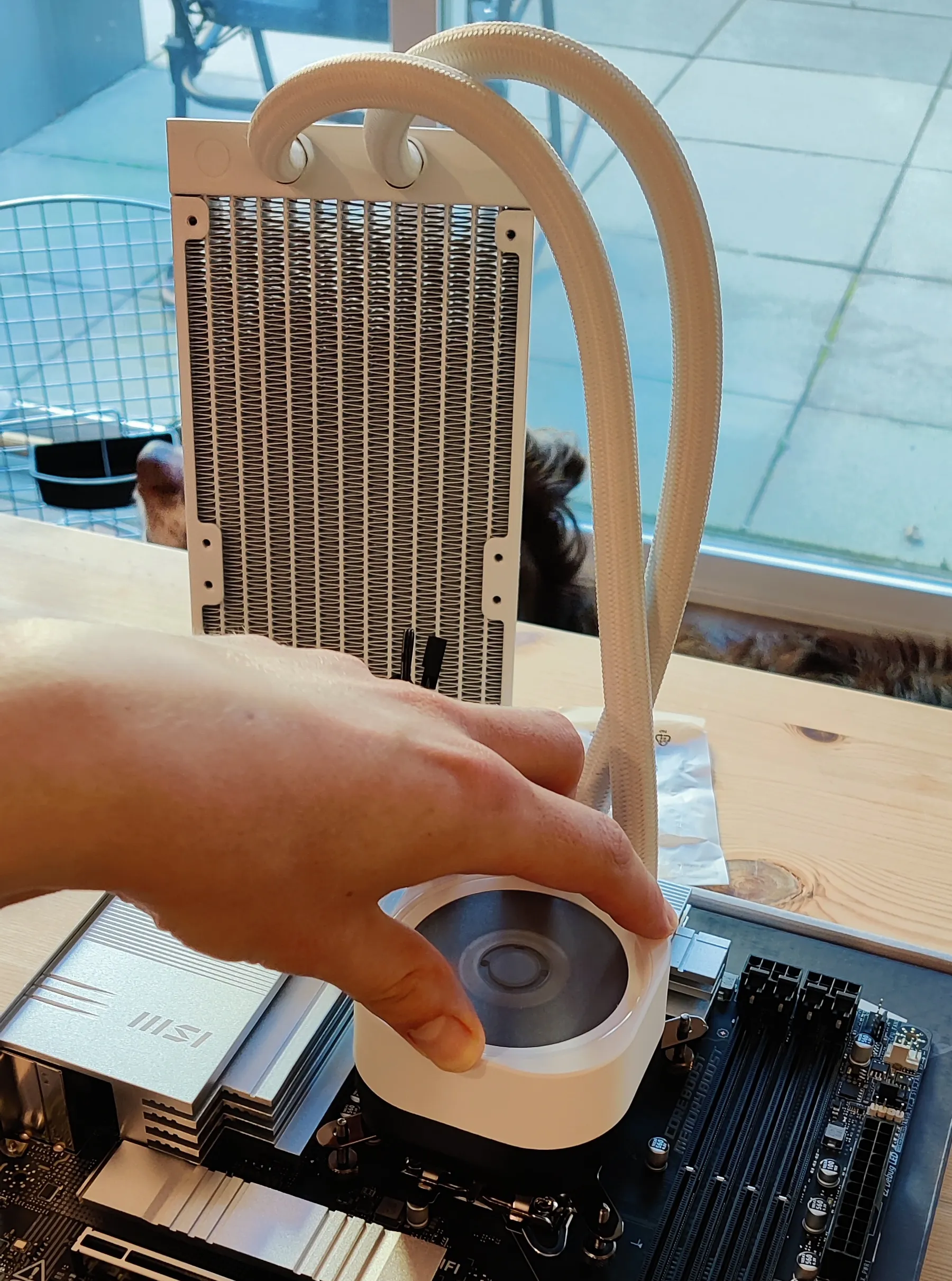 An all-in-one cooler being manually held in place over a CPU on a motherboard