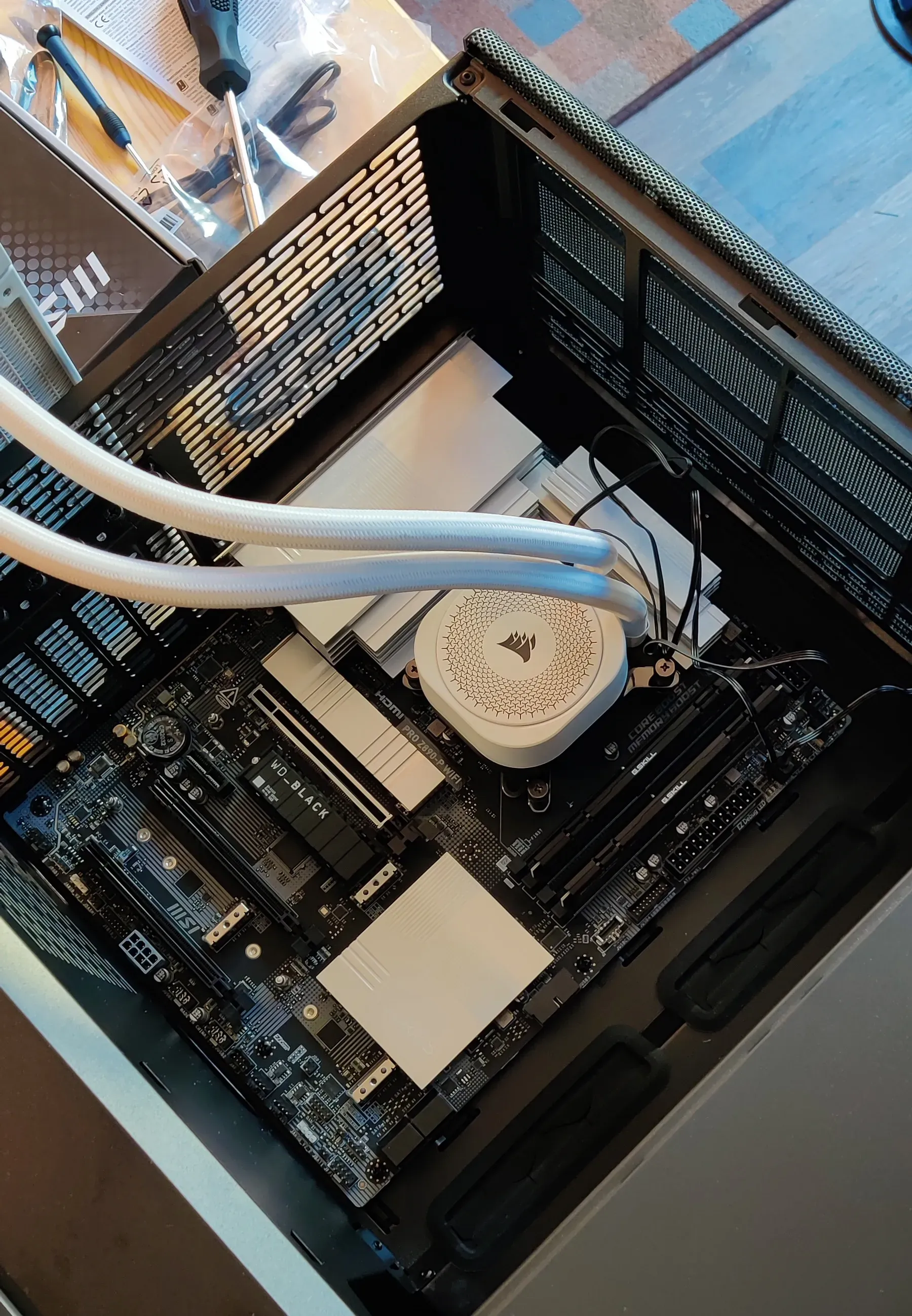 A partially assembled computer placed in a case. AIO cooler hoses and loose cables are visible.