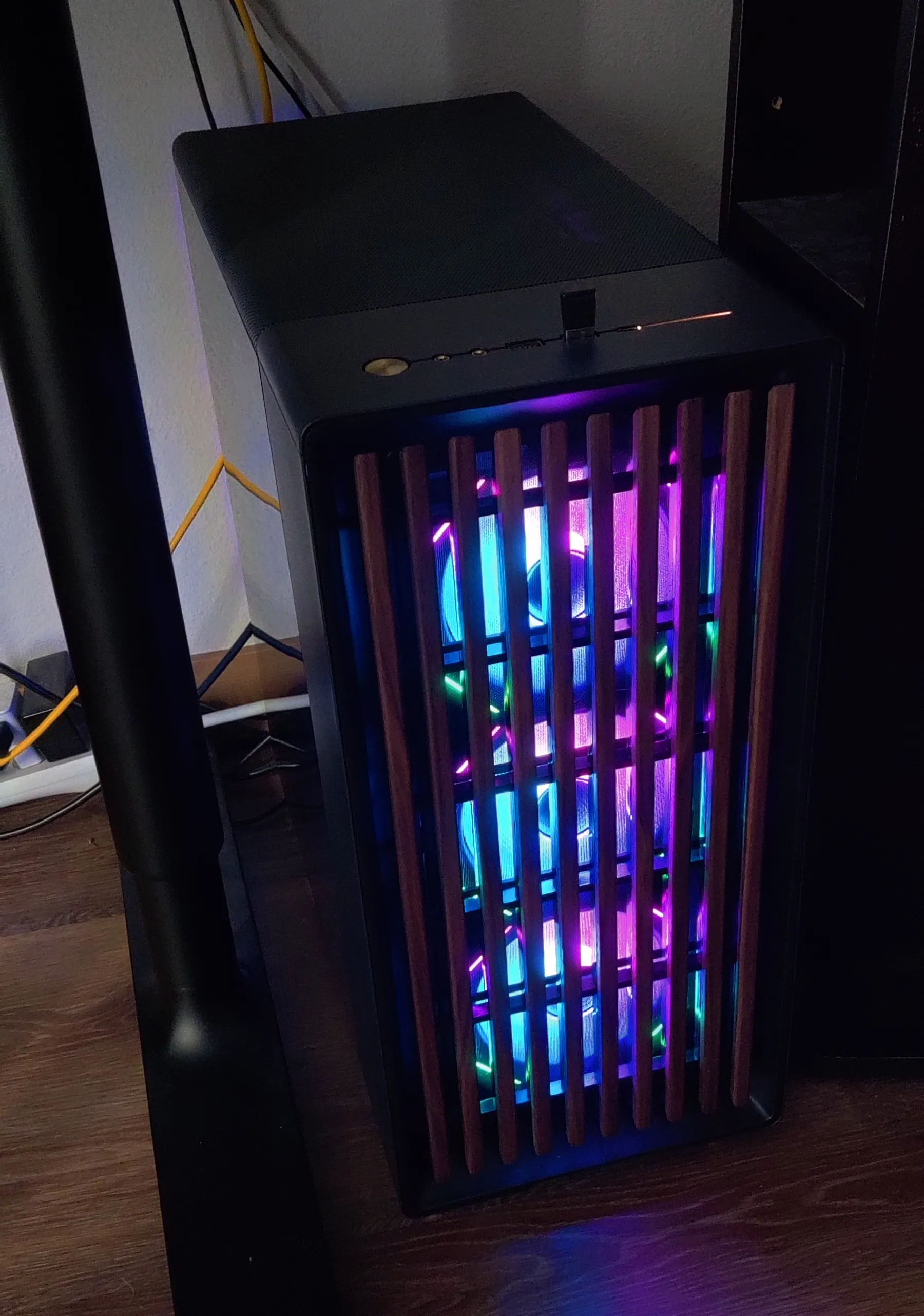 Desktop computer in the dark with vertical wooden slats and 3 lit RGB fans