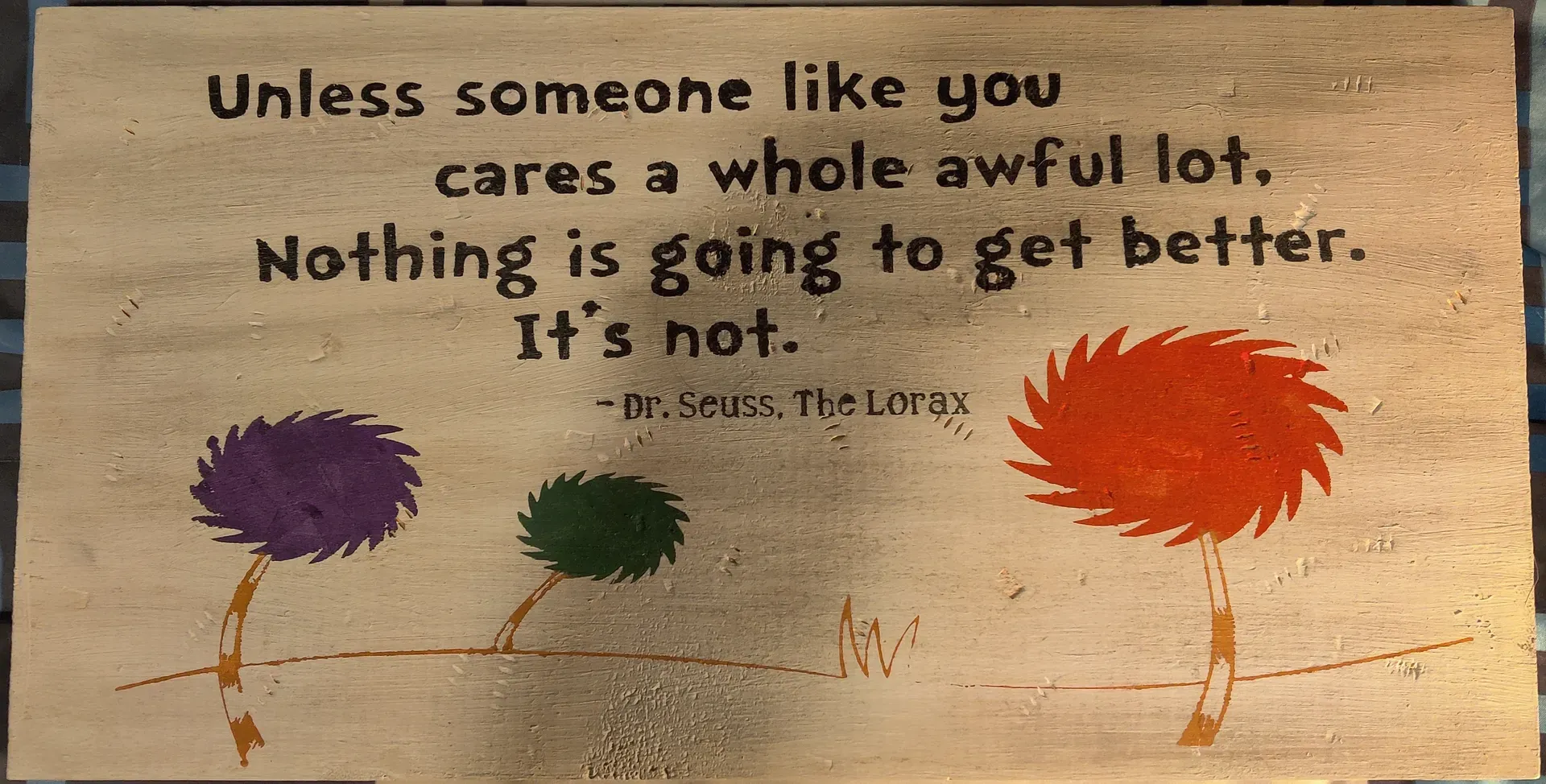 White wood board with quote: Unless someone like you cares a whole awful lot, nothing is going to get better, it's not. Dr. Seuss, the Lorax