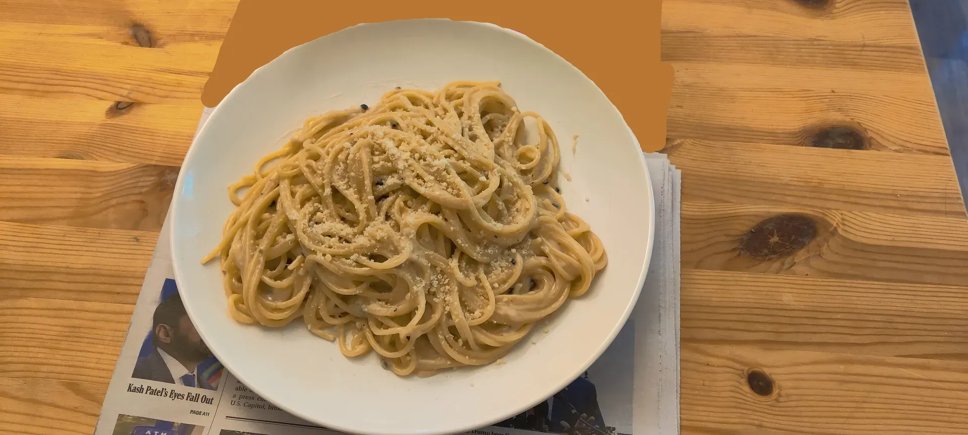 Homemade cacio e pepe on a white plate on a brown table